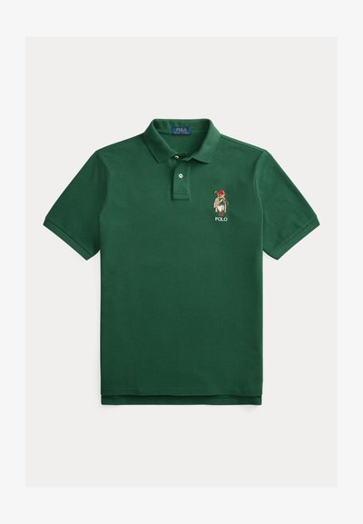 Temno zelena bombažna polo majica. Ima klasičen ovratnik, trojni gumb na sprednji strani in vezen logotip na levi strani prsnega koša. Kratki rokavi.