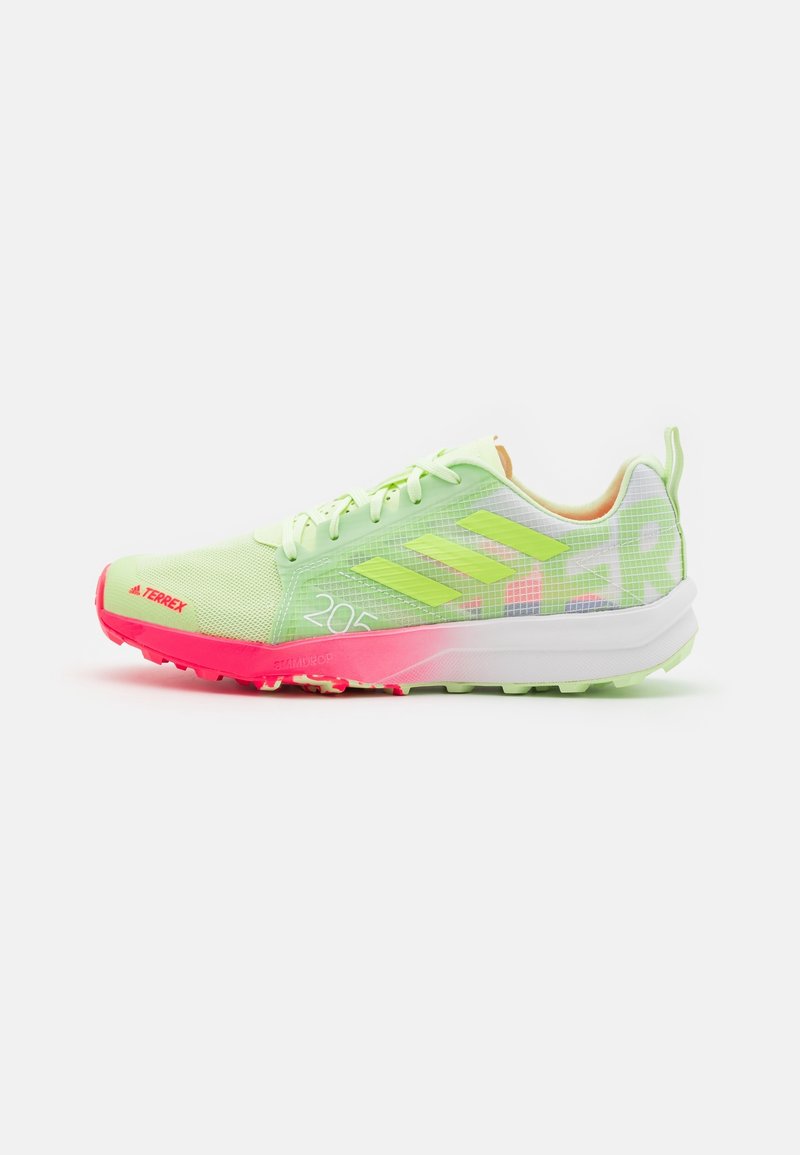 Chaussure de trail running Adidas Terrex vert clair avec semelle rose néon et trois bandes réfléchissantes sur le côté.