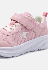 Pink athletic shoe with mesh and synthetic leather upper. White rubber sole, lace closure, and Velcro strap. Champion logo detail.