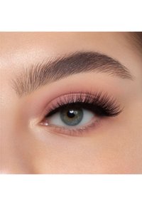 Närbild av ett öga med långa, mörka ögonfransar, mjuk rosa ögonskugga och välsorterade ögonbryn. Irisen är grön med grå nyanser.