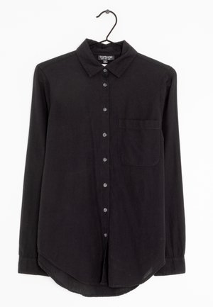 Musta pitkähiha paita, kevyt kangas, jossa on napitettava edusta, kaulus ja yksi rintatasku.