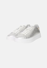 Sneakers in pelle argentata con lacci bianchi, suola bianca spessa e dettagli di branding in rilievo sul lato. Finitura liscia e lucida.