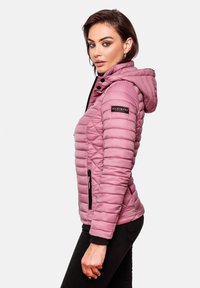 Pink padded jacket with a hood, featuring a diamond quilted design, zippered side pockets, and a logo patch on the sleeve.