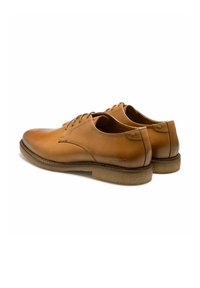 Chaussures en cuir tan avec une finition lisse, bout arrondi, design à lacets et semelle en caoutchouc texturée. Présente des coutures et un logo sur le talon.