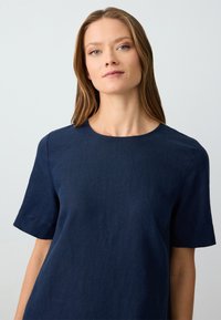 Marineblaues Leinenoberteil mit rundem Ausschnitt und kurzen Ärmeln, mit lockerer Passform und glatter Textur. Einfaches, minimalistisches Design.