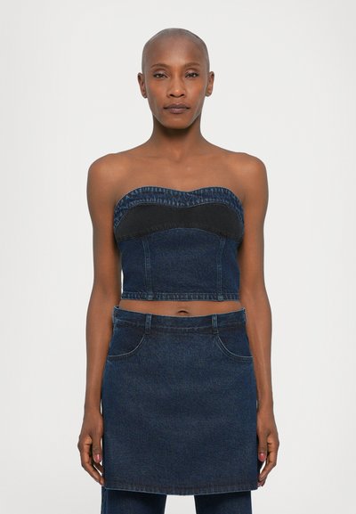 Denim crop top with a sweetheart neckline, featuring a dark blue band and light blue fringing, paired with a matching denim skirt.