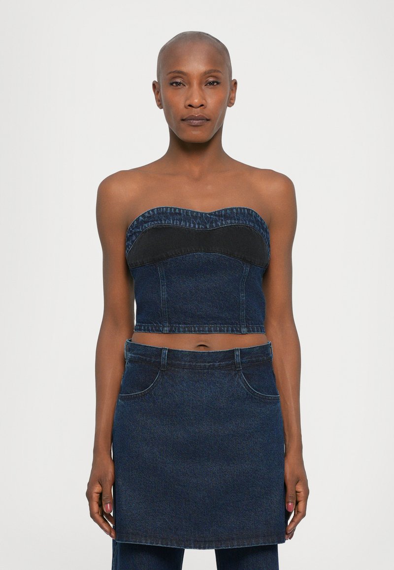 Denim crop top with a sweetheart neckline, featuring a dark blue band and light blue fringing, paired with a matching denim skirt.