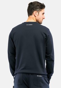 Felpa blu navy con maniche lunghe, collo rotondo e logo discreto sulla parte posteriore. Realizzata in un tessuto liscio, presenta una vestibilità comoda.