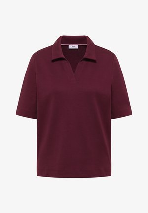Polo à manches courtes en bordeaux profond, coupe décontractée avec un col en V ouvert, étiquette "Cecil" à l'intérieur.