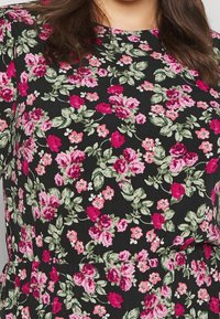 Schwarzes Blumenkleid mit lebhaften rosa und rosafarbenen Blumen sowie grünen Blättern. Glattes Material mit lockerer Passform und kurzen Ärmeln.