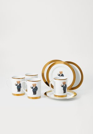 Conjunto de canecas e pratos brancos com bordas douradas, apresentando um urso vestido de fraque e segurando uma bebida em cada peça.