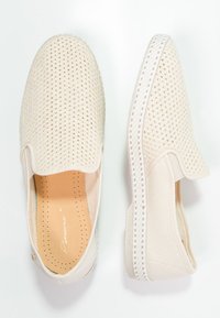 Lichtbeige instap schoenen met een ademend mesh bovenwerk, witte elastische zijkanten en een textuurzool met subtiele perforaties.