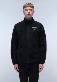 Black fleece jacket with a zip front, textured fabric, high collar, and a small logo on the chest. Features a solid black design.