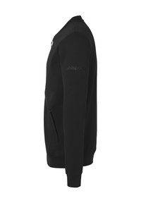Sweat-shirt noir avec une poche zippée, des poignets et un col côtelés, présentant une texture lisse et un logo subtil sur la manche.