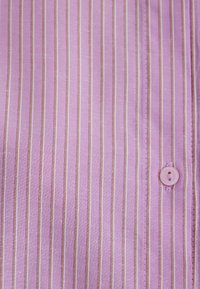 Purple striped fabric with narrow light brown lines, featuring a button closure and visible stitching details. Soft texture.