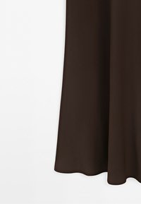 Close-up of the lower half of a dark brown fabric garment against a white background.