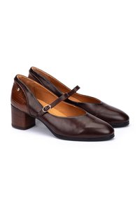 Chaussures Mary Jane en cuir marron avec un bout rond, une sangle de cheville et un talon texturé. Présente un upper lisse et un talon bloc au style bois.