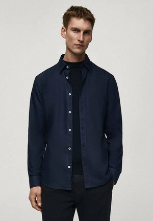Marineblauw overhemd met kraag, lange mouwen en een soepele textuur. Voorzien van witte knopen en een relaxte pasvorm.