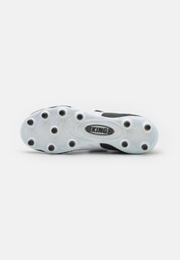 Suela de bota de fútbol en blanco y negro con una superficie texturizada, tacos circulares y un logotipo central que dice "KING" en un óvalo.