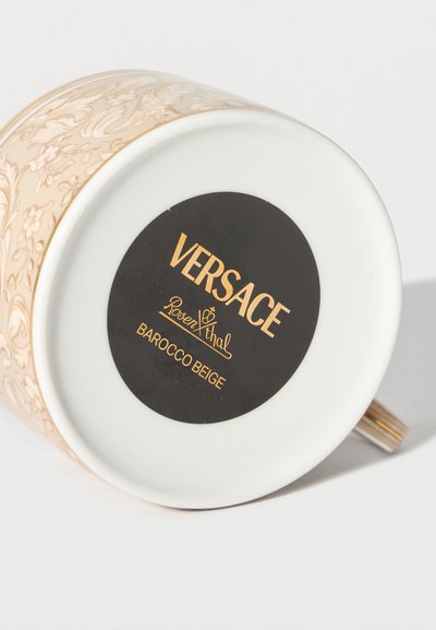 Bottom of beige and gold floral patterned porcelain cup with black and gold Versace Rosenthal Barocco Beige label.