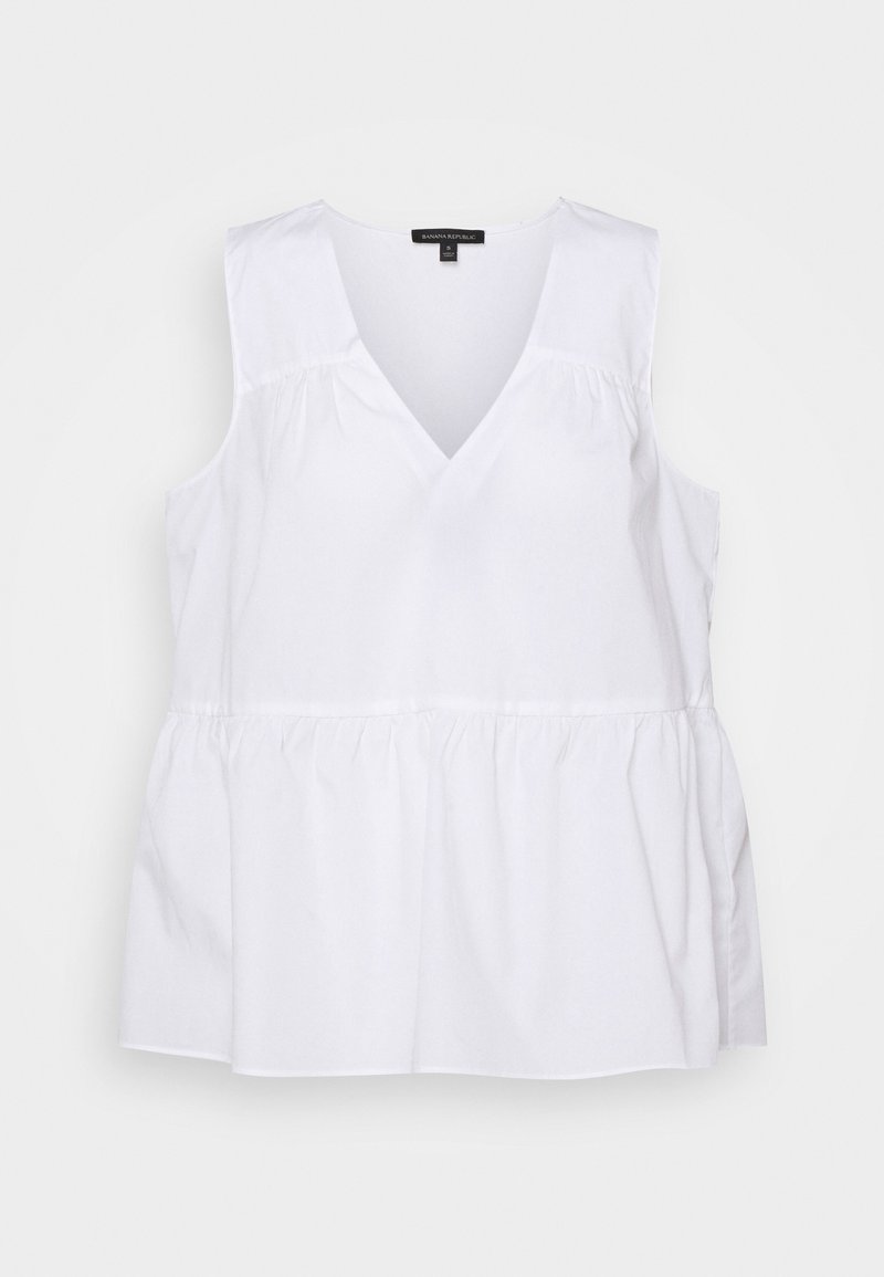 Blouse blanche sans manches avec col en V, taille froncée et coupe ample, fabriquée en tissu léger.