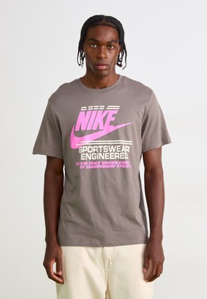 Grå bomulds t-shirt med et pink Nike-logo og tekst med vandrette striber. Korte ærmer og en afslappet pasform. Ingen synlige mønstre.