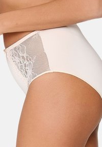 Højtaljede trusser i lys rosa med blonder og netdetaljer på siden, glat tekstur og et enkelt design.