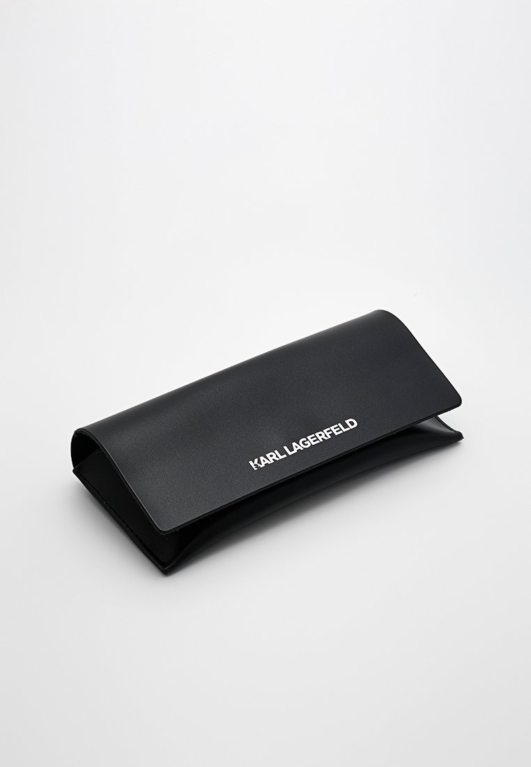 Étui à lunettes rectangulaire noir avec un rabat, arborant le texte blanc "KARL LAGERFELD" sur le dessus, présenté fermé sur une surface blanche.