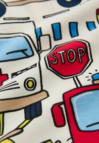 Tissu en coton présentant des illustrations multicolores de véhicules d'urgence, de panneaux d'arrêt et d'éléments de route, avec des détails en noir.