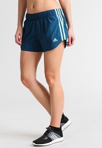 Laivastonsiniset urheilushortsit, jotka on valmistettu kevyestä materiaalista; niissä on joustava vyötärönauha ja vaaleansiniset pystysuorat raidat sivuilla.