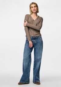Brun ribbad cardigan med V-hals och knappstängning, kombinerad med ljusblå vida jeans med en urtvättad textur och sid sömmar.