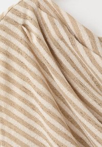 Tissu tricoté doux avec des rayures horizontales beige et blanc, présenté avec de légers plis sur une surface plate.