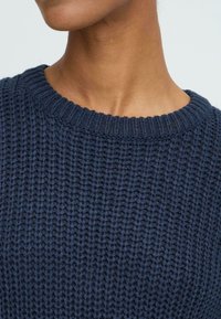 Marineblå strikket sweater med en ribbenet rund halsudskæring, der har et tekstureret mønster og medium tykkelse. Blødt materiale, casual design.