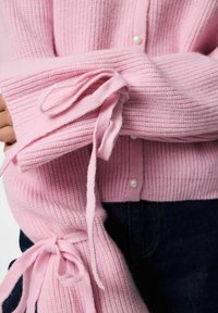 Rozā ribota džemperis ar pogu aizdari, rotātām ar mazām pērļu detaļām un saitēm uz piedurknēm, strukturēta auduma un brīvā piegriezuma.