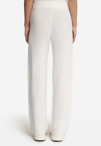 Vidbenade byxor i mjukt vitt tyg med en slät yta och elastisk midja. Har en minimalistisk design och en flödande silhuett.