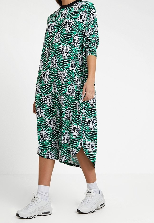 Grön klänning med svarta accenter, med ett mönster av tiger- och zebrastripes. Längd till halvkalv, lös passform och sidoklämmor för rörlighet.