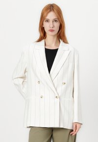 Bela dvoredna blazer jakna z navpičnimi črnimi črtami, ki ima dve sprednji žep in zlate gumbe ter strukturirano silhueto.