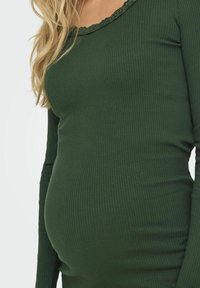 Långärmad grön ribbad topp med en scalloped halsringning och en figurnära passform, designad för komfort och stretch runt midjan.