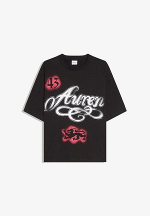 Musta puuvillainen t-paita, jossa on suuri valkoinen käsinkirjoitusteksti "Auren", punainen "43" ja punainen leijonakuva pehmeällä taustalla. Lyhyet hihat.