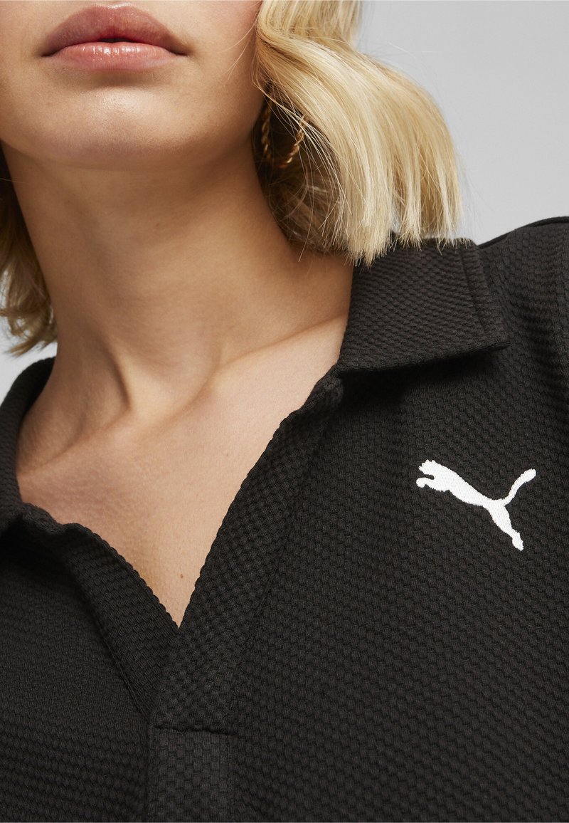 Polo nero con un motivo testurizzato, caratterizzato da un logo Puma bianco sul petto e un design di colletto classico.