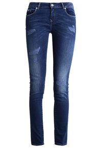 Pantalones vaqueros ajustados en denim azul oscuro con parches desgastados, diseño de cinco bolsillos y detalles de costura en tono claro. Textura suave con ligero desgaste.