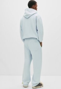 Lichtblauwe hoodie met een voorzak, gecombineerd met bijpassende sweatpants met een achterzak. Gemaakt van zacht, textuurmateriaal.