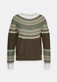 Grüner, gemusterter Pullover mit rundem weißem Ausschnitt. Mit geometrischen Mustern in Dunkel- und Hellgrün über Brust und Ärmeln.