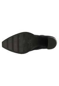 Semelle de botte noire avec un motif de grip texturé et un bout pointu, vue de dessous.