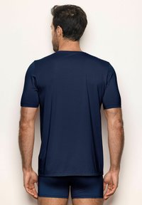 T-shirt bleu marine à manches courtes avec une texture lisse, un design ajusté et un col rond, accompagné de shorts sombres assortis.