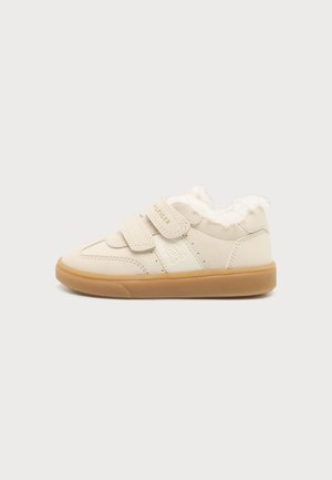 Baskets beige pour enfants avec deux bandes Velcro, doublure en fausse fourrure, logo embossé sur le côté et semelle en gomme sur fond uni.