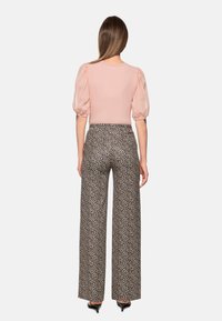 Pink puff-sleeve top with a round neckline paired with high-waisted wide-leg pants featuring a black and brown leopard print pattern.