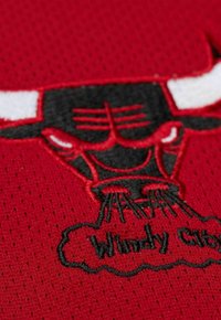 Red mesh fabric featuring an embroidered black and white bull's head logo with "Windy City" in script beneath it, textured stitching detail.