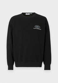 Črna dukserica iz bombaža s krožnim izrezom, dolgimi rokavi in ribastimi manšetami. Na prsih ima belo vezeno logo.