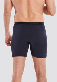 Marineblaue Herrenboxershorts aus weichem, elastischem Stoff mit einem schwarzen elastischen Bund und glatter Oberfläche, entworfen für Komfort und Passform.
